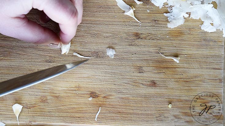 Cutting the tip off a garlic clove that wasn't cut the first time around.