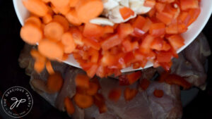 Adding the vegetables to the crock, over the chicken.