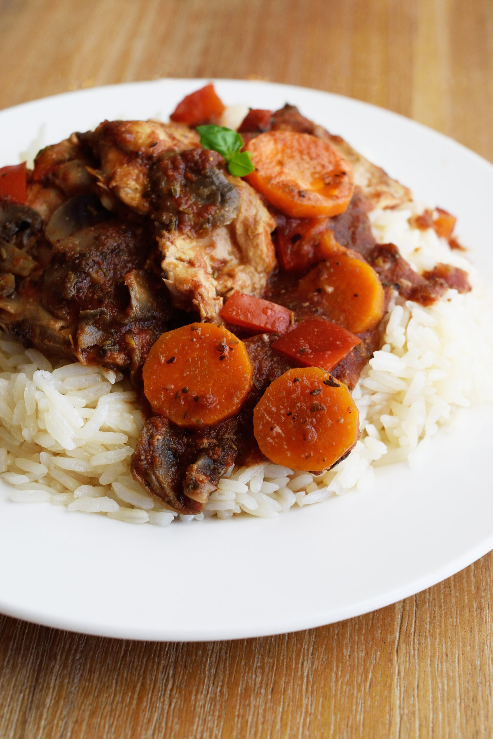 Slow Cooker Chicken Cacciatore served over a bed or rice on a white plate.