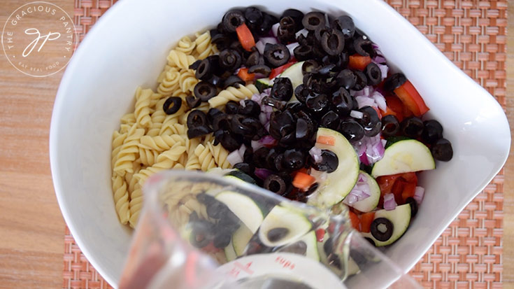 Adding the dressing to the pasta salad.