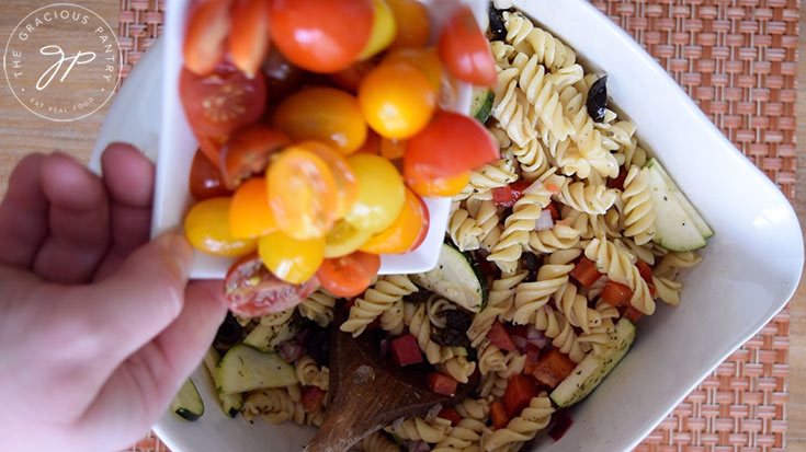 Stirring the cut tomatoes into the pasta salad.