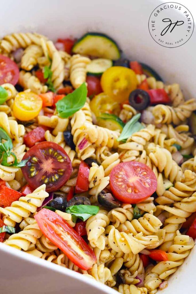 A micro shot of this Vegetable Pasta Salad shows pasta, tomatoes, basil and zucchini.