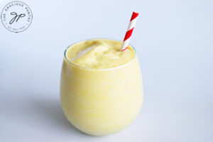 The finished Virgin Pina Colada Recipe in a stemless wine glass with a red and white stripped straw.