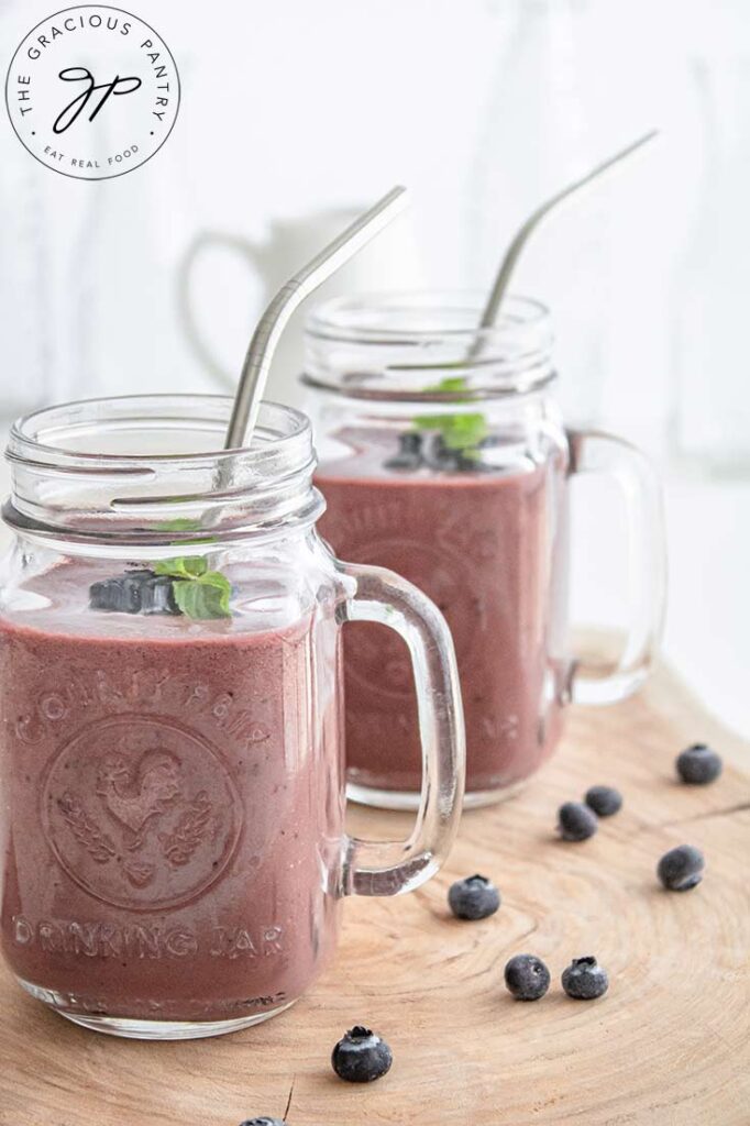 An up close shot of mugs filled with this smoothie and topped with mint leaves and metal straws.