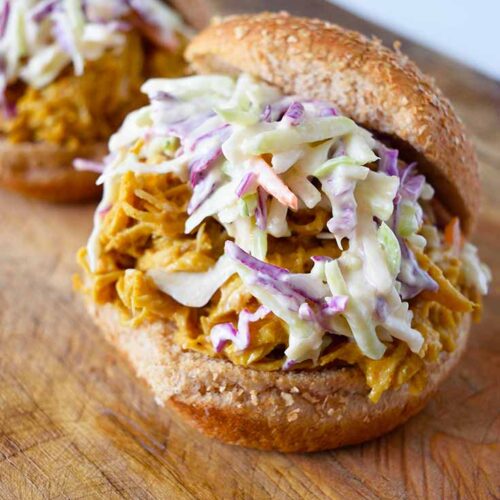 Two Carolina Gold BBQ Chicken Sandwiches with the top bun sitting off to the sides of the sandwiches.