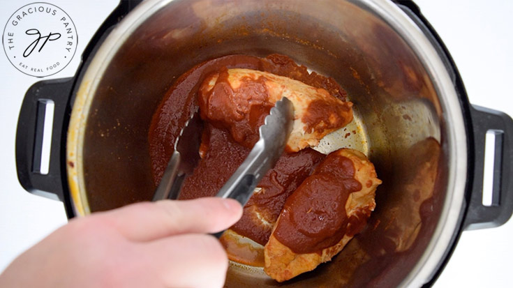 Sautéing the chicken in sauce in the Instant Pot on the sauté setting.