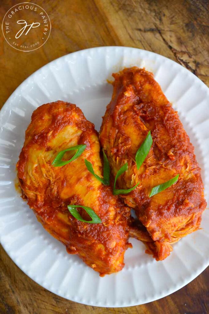 An overhead view of two Crockpot BBQ Chicken Breasts sitting on a white plate.