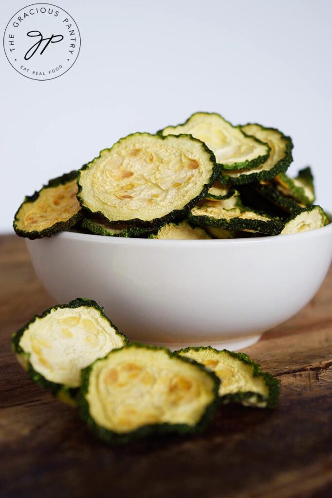 A white bowl filled with dehydrated zucchini chips.