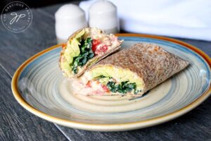 The finished, cut hummus wrap on a plate, ready to eat.