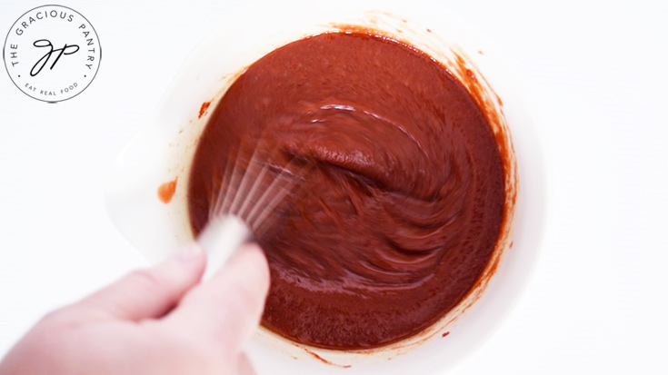 Whisking the Maple BBQ Sauce in a white mixing bowl.