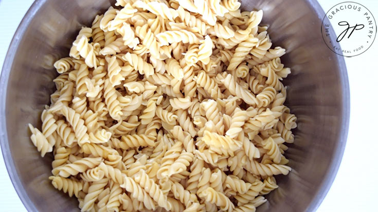 Cooked pasta in a large, stainless steel mixing bowl.