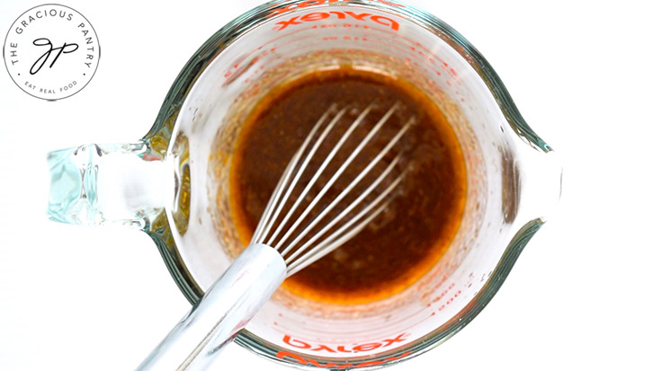 Whisking the dressing ingredients in a glass measuring cup.