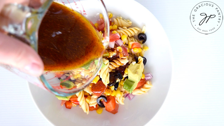 Pouring the dressing over the Mexican Pasta Salad.