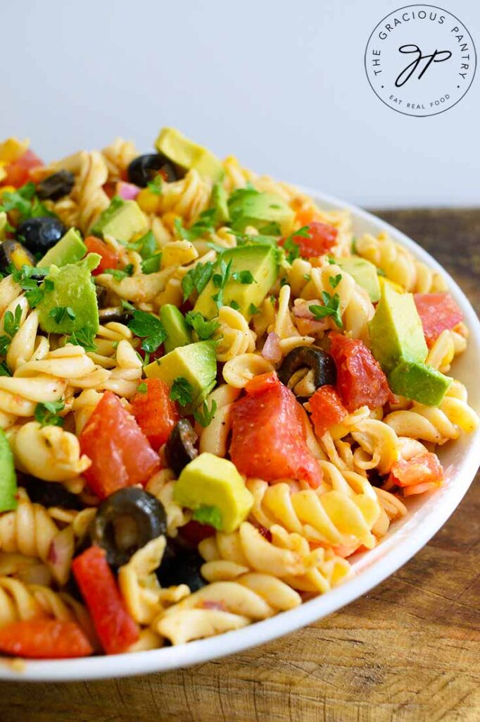 An up close shot of a white bowl completely filled with this Mexican Pasta Salad, against a white background.