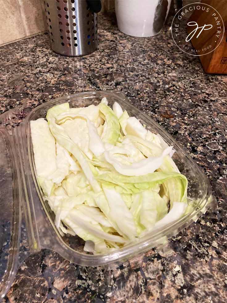 A plastic container filled with sliced green cabbage.