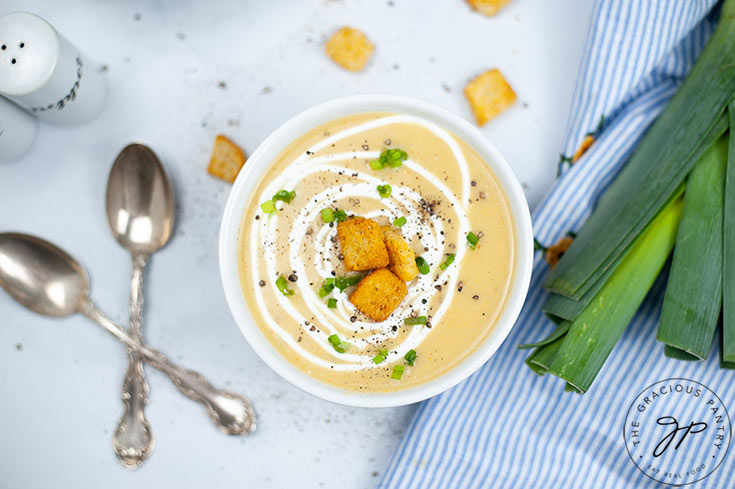 The finished Instant Pot Potato Leek Soup Recipe in a white bowl with croutons sprinkled on top.