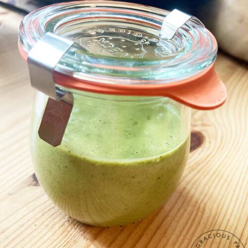 A small canning jar filled half way with this Lemon Basil Dressing Recipe. The lid is on and two metal clamps hold the lid down.