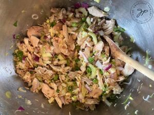 Mixing the lemon chicken salad ingredients together in a large, stainless steel mixing bowl.