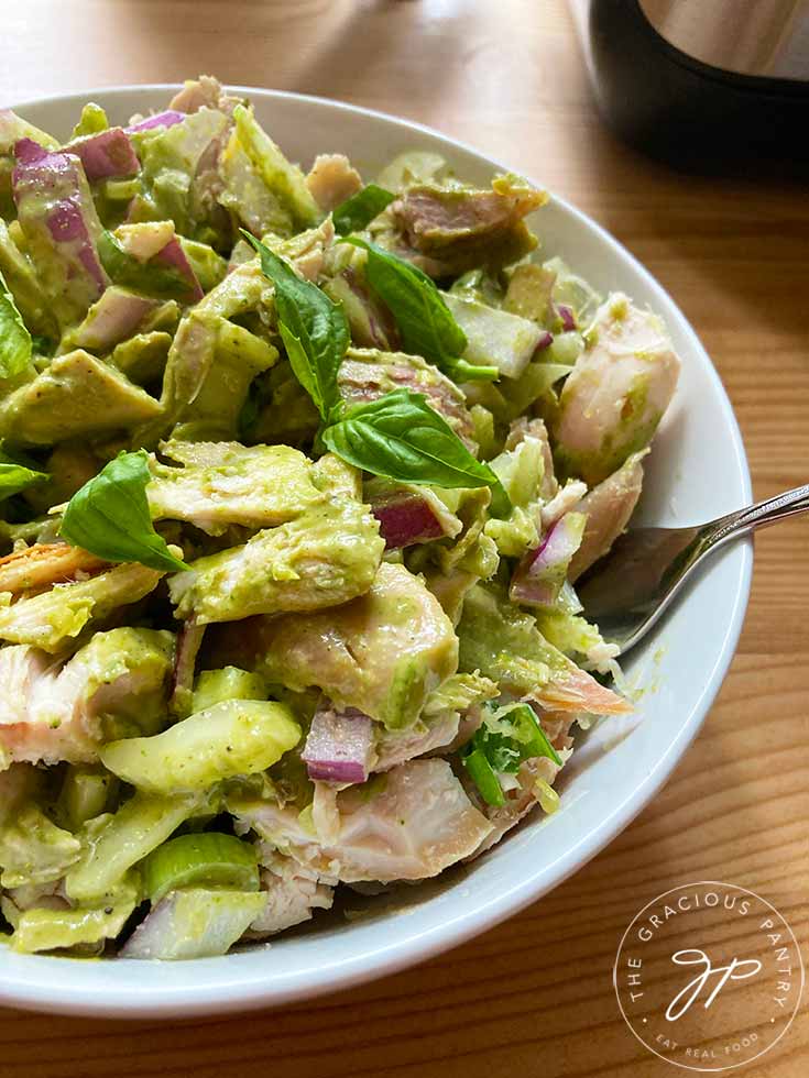 Lemond chicken salad in a white bowl with fresh basil leaves garnishing the top.