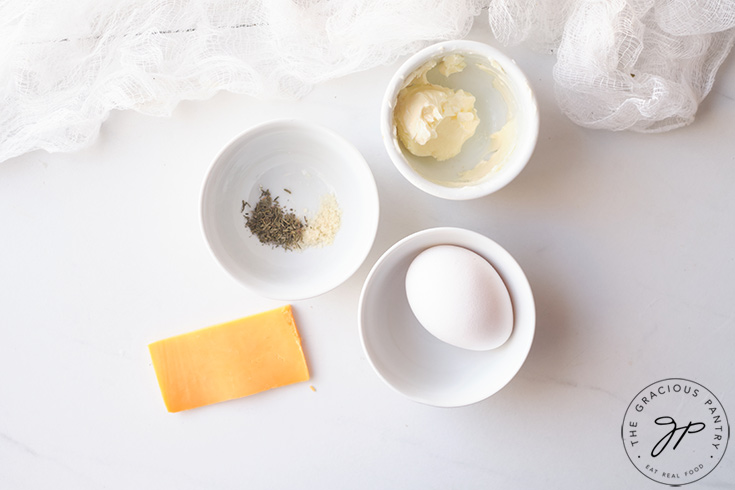 Small, white bowls collected on a white surface, filled with recipe ingredients.