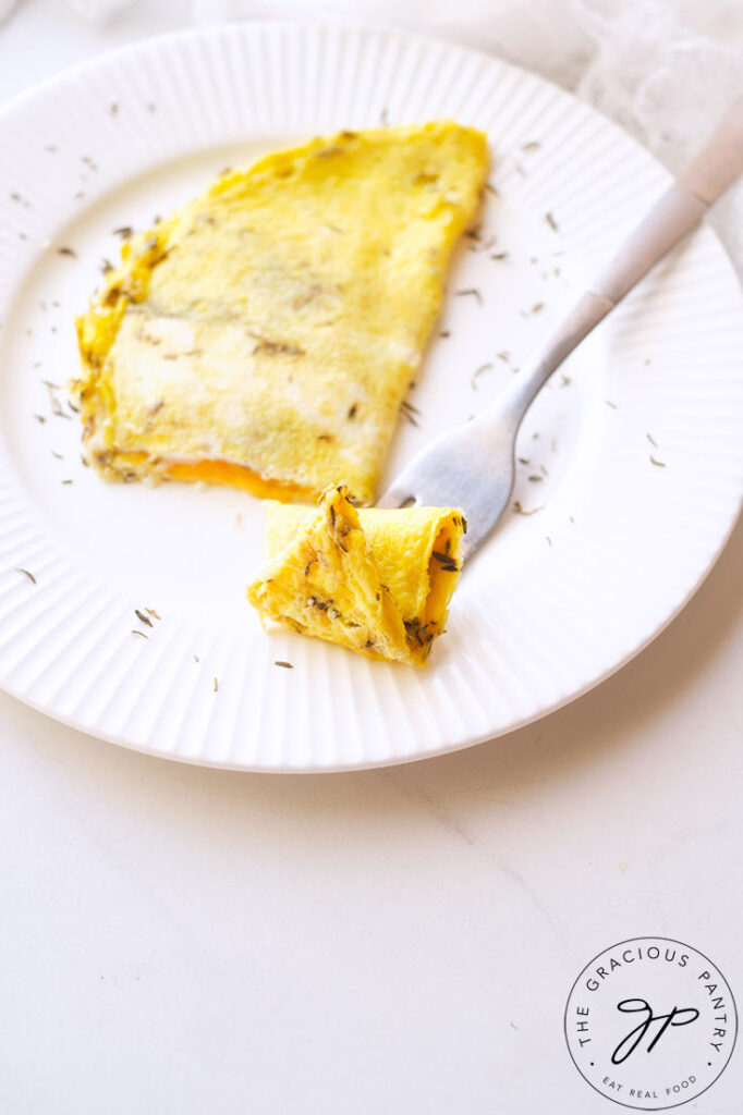 A side view of the omelet on a white plate with a fork holding the first bite.