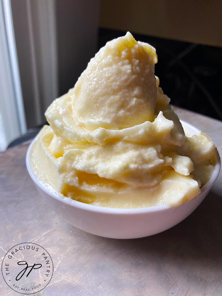 A white bowl filled with Pineapple Whip, piled high in the bowl.