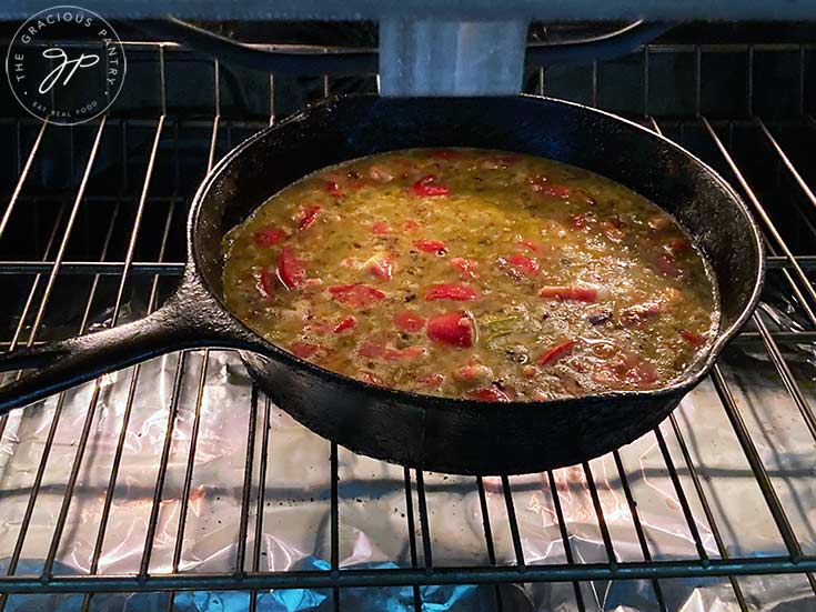 The finished egg mixture in a cast iron skillet, sitting on a shelf in the oven to bake.