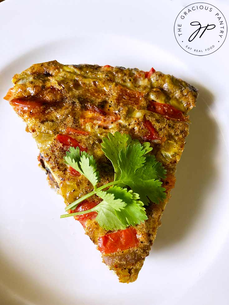 An overhead view looking down onto a single slice of Southwestern Crustless Quiche on a white plate.