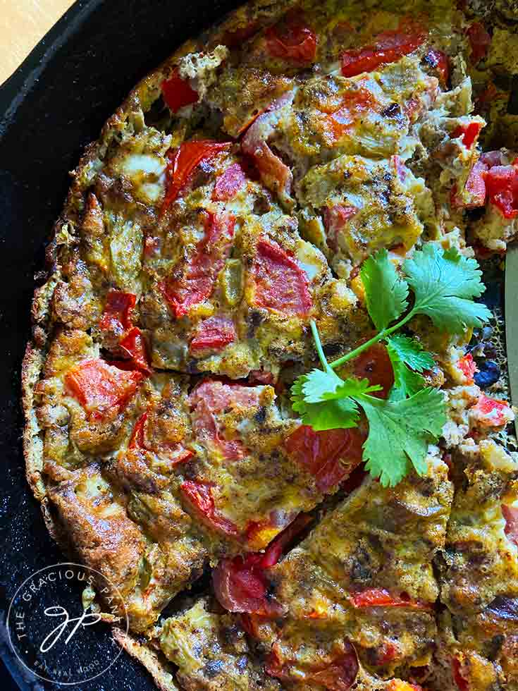 The Southwestern Crustless Quiche sliced in the skillet it was cooked in. A bit of fresh cilantro sits on top for garnish.