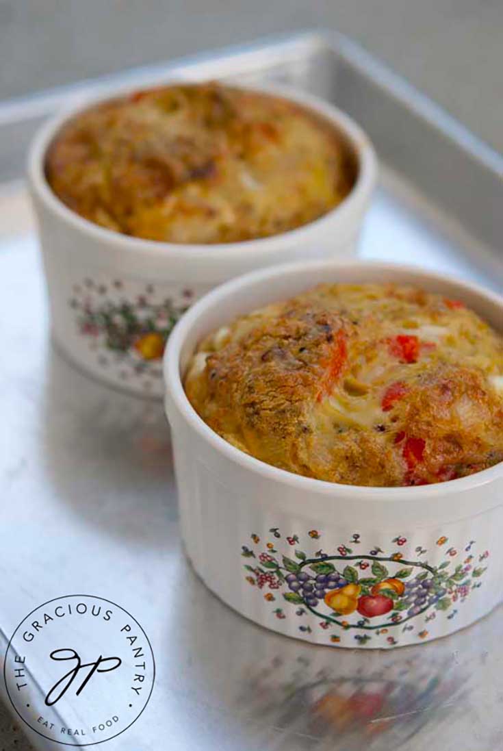 Two small ramekins sit on a cookie sheet with just baked Southwestern Crustless Quiche in each of them.