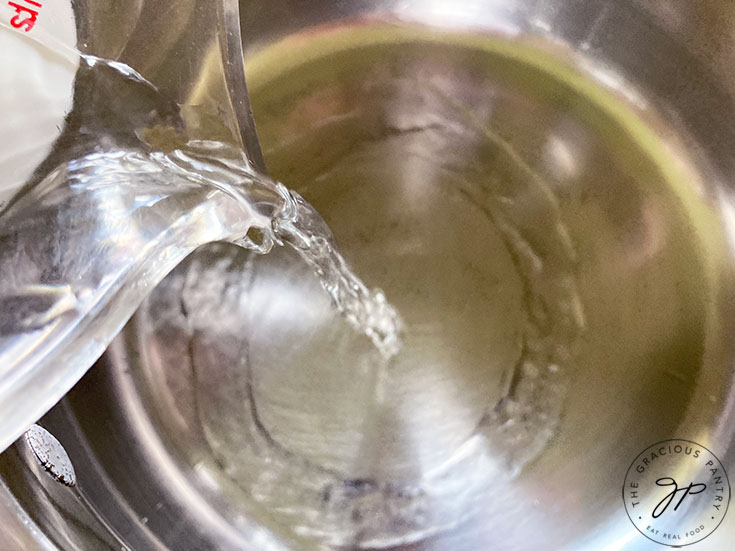 Pouring vinegar and water into a pot.