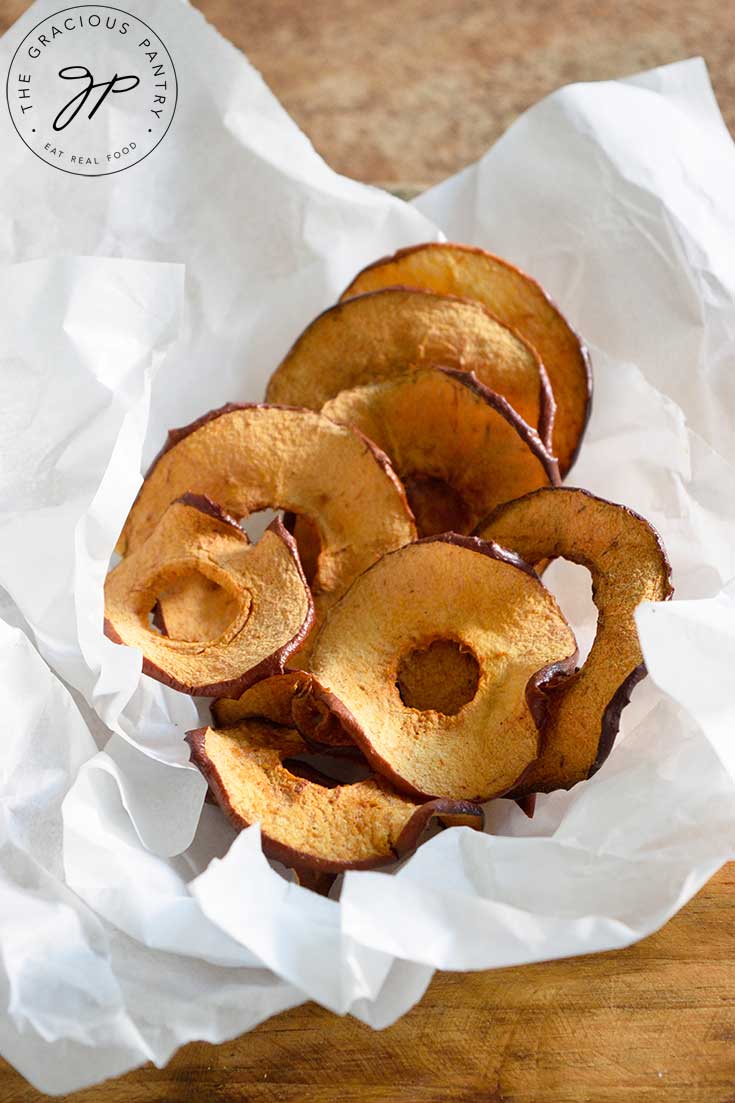 An overhead view looking down into a basked of Air Fryer Apple Chips in crinkled parchment paper.
