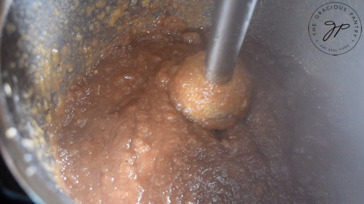 Blending the cooked ingredients in the cooking pot with an immersion blender.
