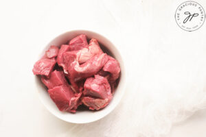 Raw bison stew meat in a white bowl.