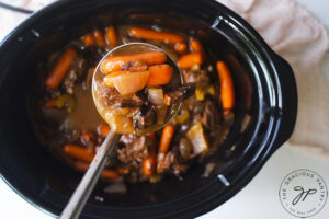 A ladle holding some of the Bison Stew Recipe up to the camera.