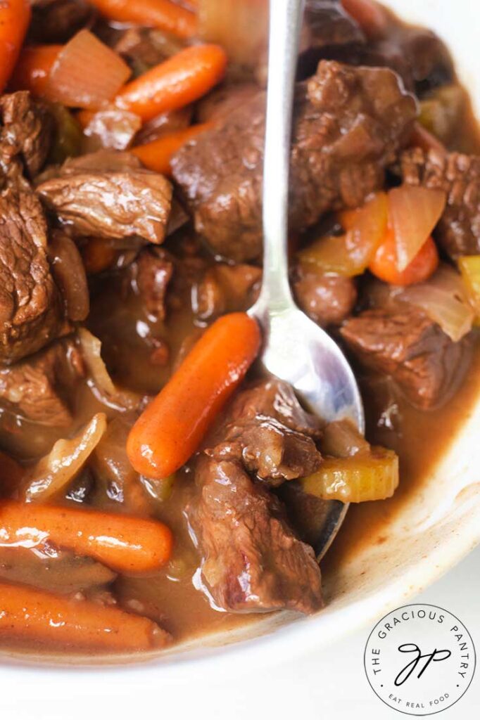 A white bowl with a silver spoon, picking up some of the bison stew from the bowl.