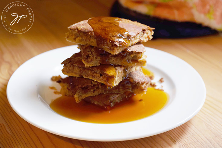 The finished Cinnamon Swirl Pancakes served on a white plate with maple syrup over the top.