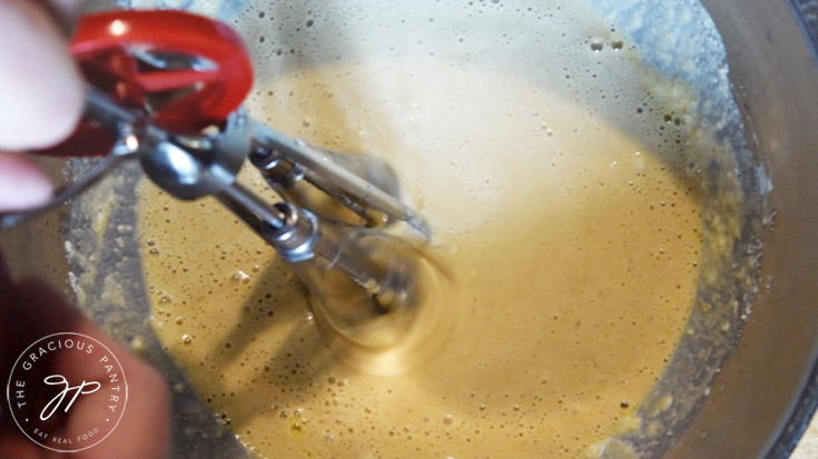 Mixing the wet ingredients into the dry ingredients with a hand mixer.