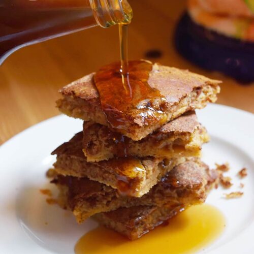 Maple syrup being poured over served Cinnamon Swirl Pancakes.