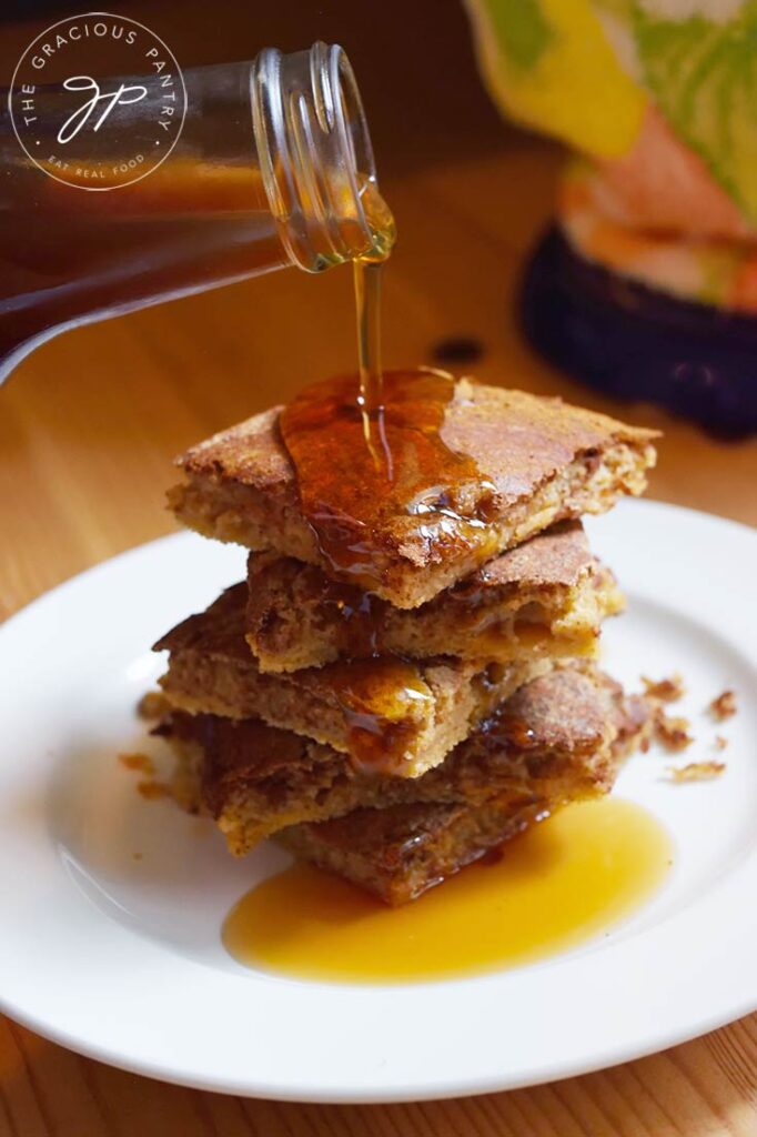 Maple syrup being poured over served Cinnamon Swirl Pancakes.