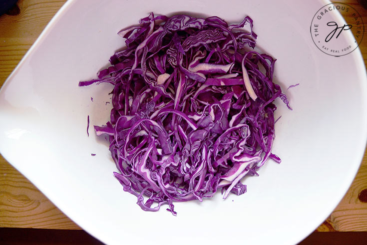 The shredded red cabbage in a large white mixing bowl.