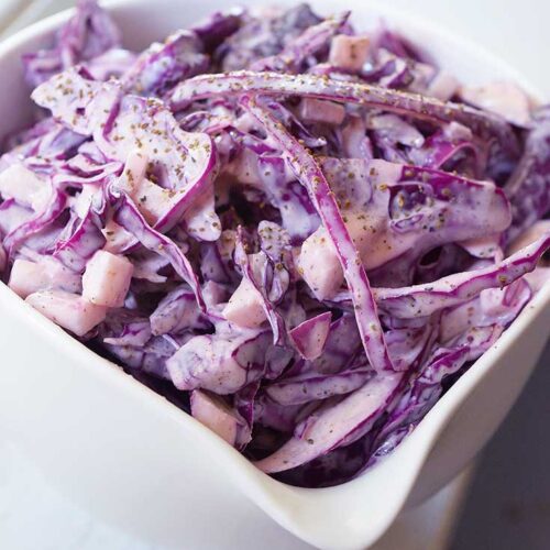 Another side view of a small white bowl sitting on a windowsill, filled with this Red Cabbage Slaw Recipe.