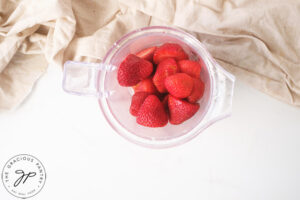Strawberries sitting in a blender cup.