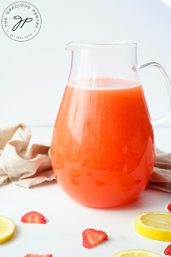 A side view of a clear pitcher filled with Strawberry Lemonade.