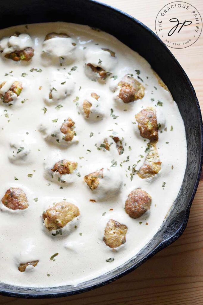 Swedish meatballs in a black, cast iron pan, sitting in a white sauce.