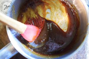 The teriyaki sauce, thickened on the stove. A basting brush sits inside the pot.