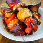 A white plate piled with glazed Teriyaki Chicken Kabobs.