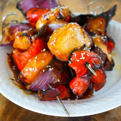 A white plate piled with glazed Teriyaki Chicken Kabobs.