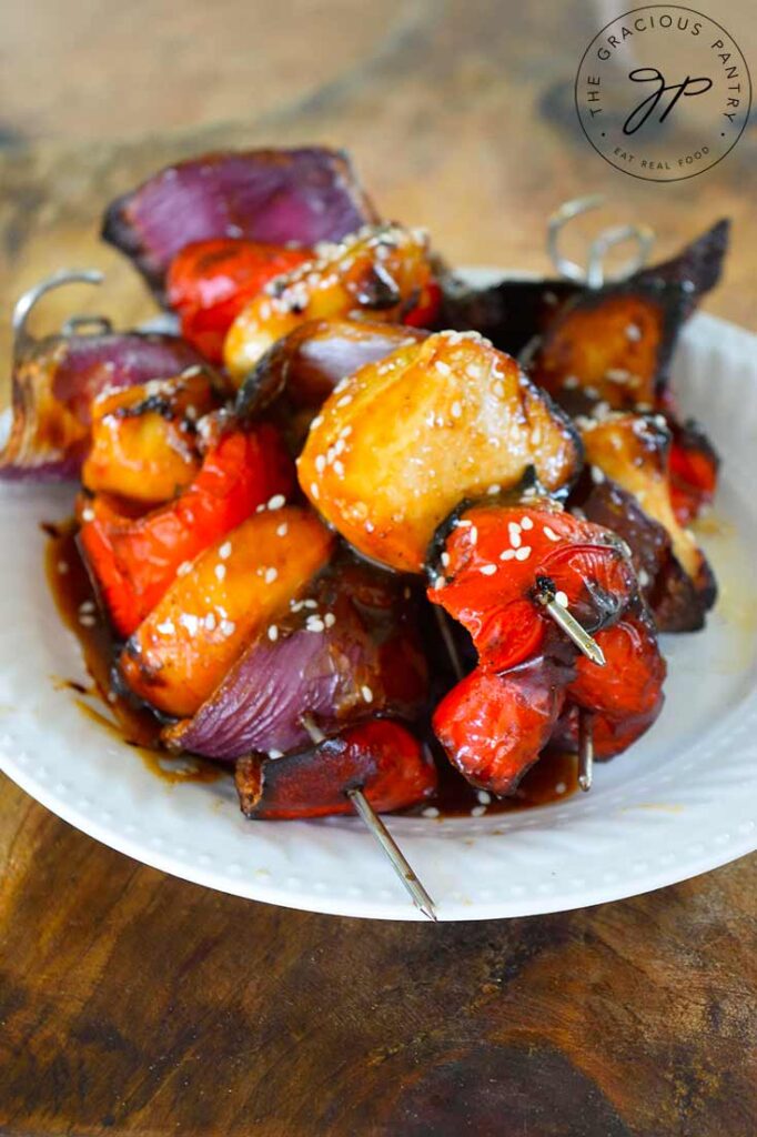 A white plate piled with glazed Teriyaki Chicken Kabobs.