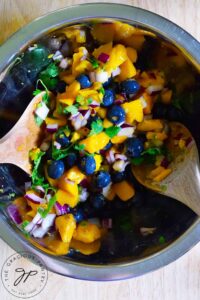 An overhead shot of the Blueberry Mango Salsa being mixed in a stainless steel mixing bowl.